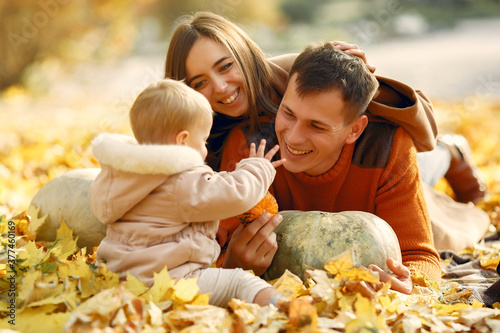 Family in a autumn park. Woman in a brown sweater. Cute little girl with parents. Family with pumpkins.