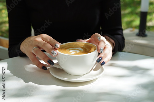 Cup of coffee latte in the hands of a girl with a beautiful manicure