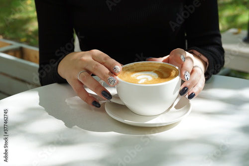 Cup of coffee latte in the hands of a girl with a beautiful manicure