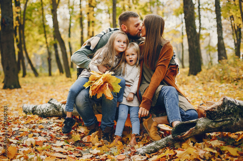 Family in a autumn park. Woman in a red sweater. Cute childrens with parents