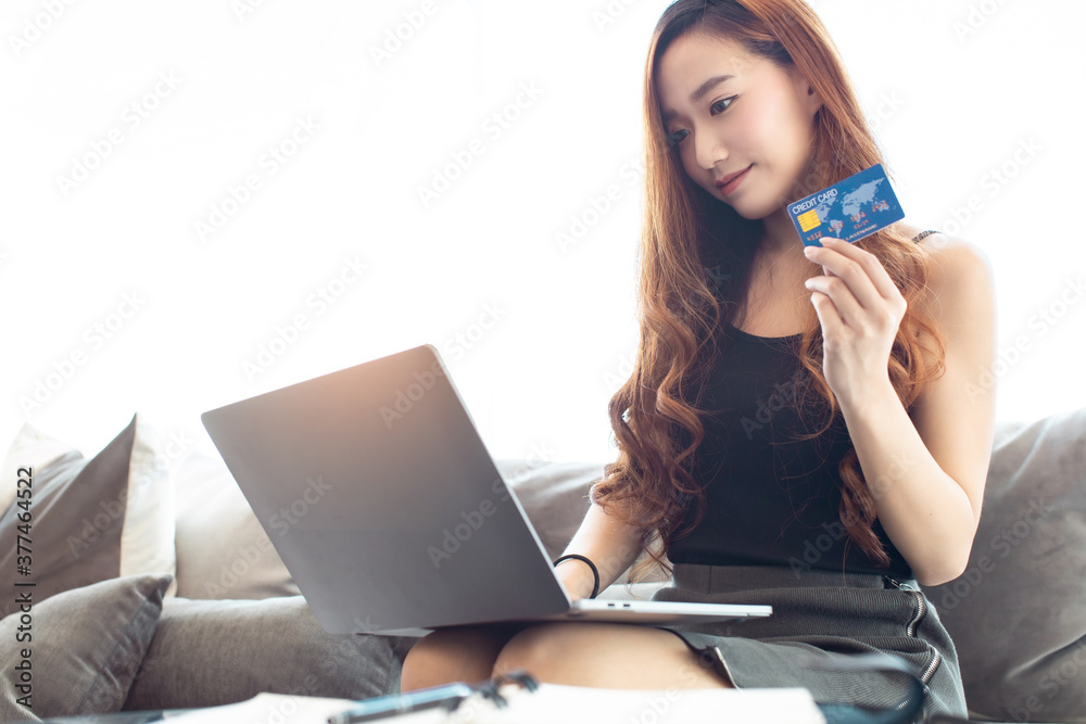 Happy Asian young woman doing online shopping at home.She holding credit card and using laptop computer.Smiling asian woman on couch using tablet to shop online the living room. Happy Asian young woman doing online shopping at home.She holding credit card and using laptop computer.Smiling asian woman on couch using tablet to shop online the living room.
