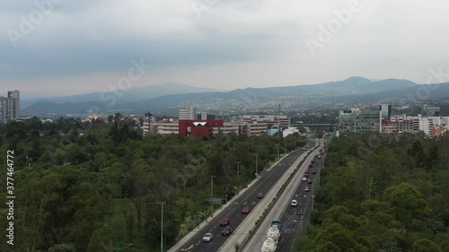 Vista aérea del tráfico sobre Av. Insurgente Sur a la altura del Centro Cultural Universitario  con el sur de la ciudad como fondo. photo