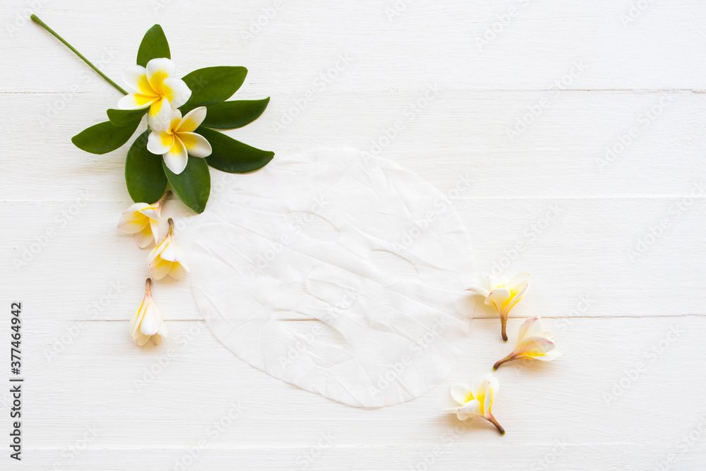 Obraz premium natural cosmetics herbal aroma sheet mask extract herbal flowers frangipani health care for skin face essence face mask arrangement flat lay style on background white