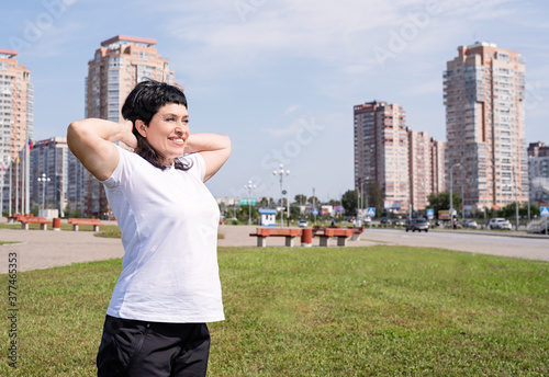 Smiling senior woman warming up before training outdoors in the park on urban background © dark_blade