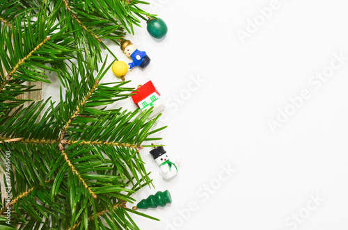 Christmas background with copy space for text and design. Fir branch and wooden christmas toys on a white sheet of paper