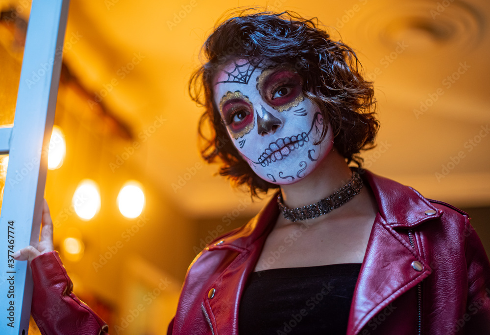 mujer joven latina mexicana maquillaje catrina calavera día de muertos  chaqueta roja cabello corto luz cálida amarilla fondo fuera de foco bokeh  aislada close up Photos | Adobe Stock