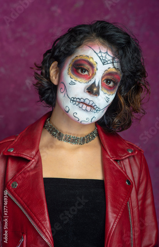 mujer joven latina mexicana maquillaje catrina calavera día de muertos chaqueta roja cabello corto fondo rosa aislada
