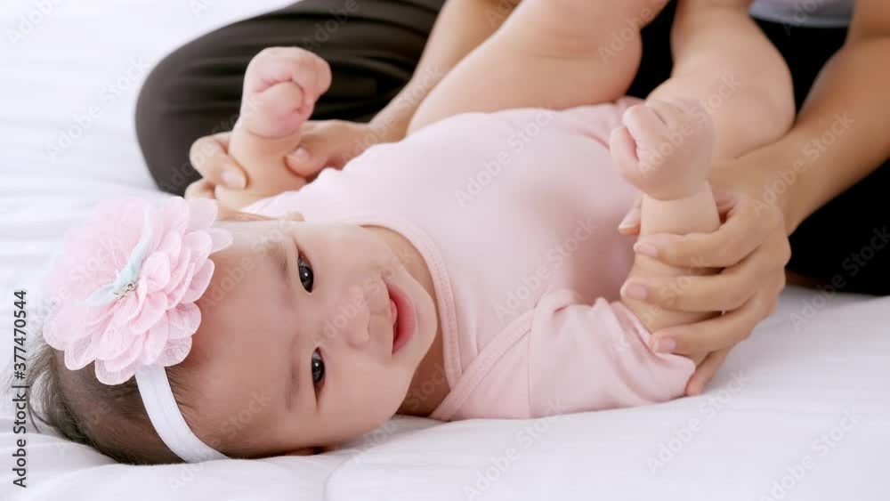 Young mother with her little baby playing on bed at home.