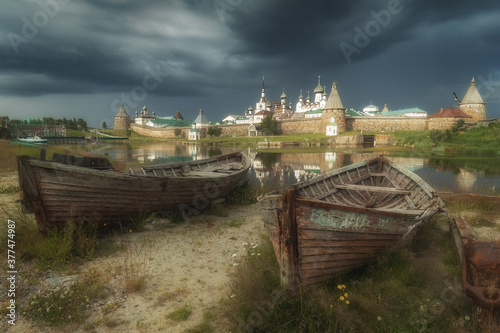 Two wooden boats on the shore and a monastery on the background