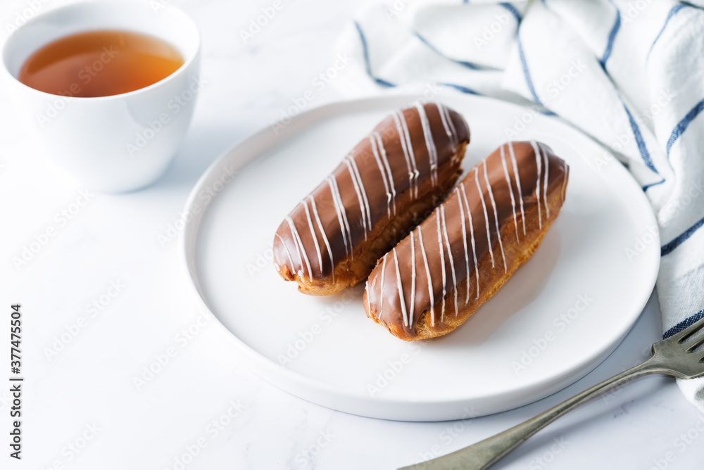 Fresh eclairs on a plate with chocolate glaze Fresh eclairs on a plate with chocolate glaze