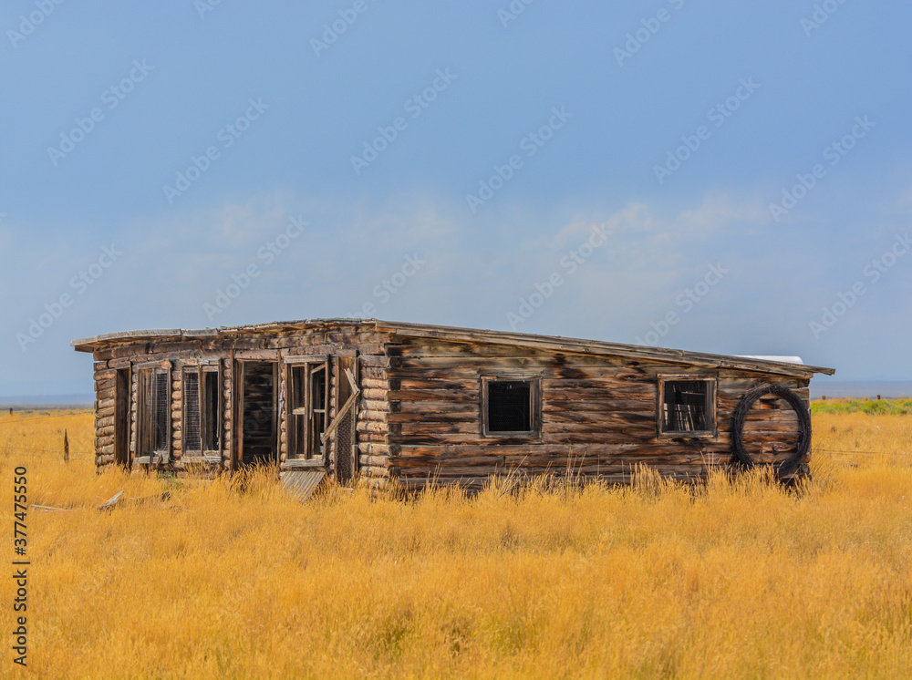 A low profile abandoned barn falling apart in rural Colorado A low profile abandoned barn falling apart in rural Colorado
