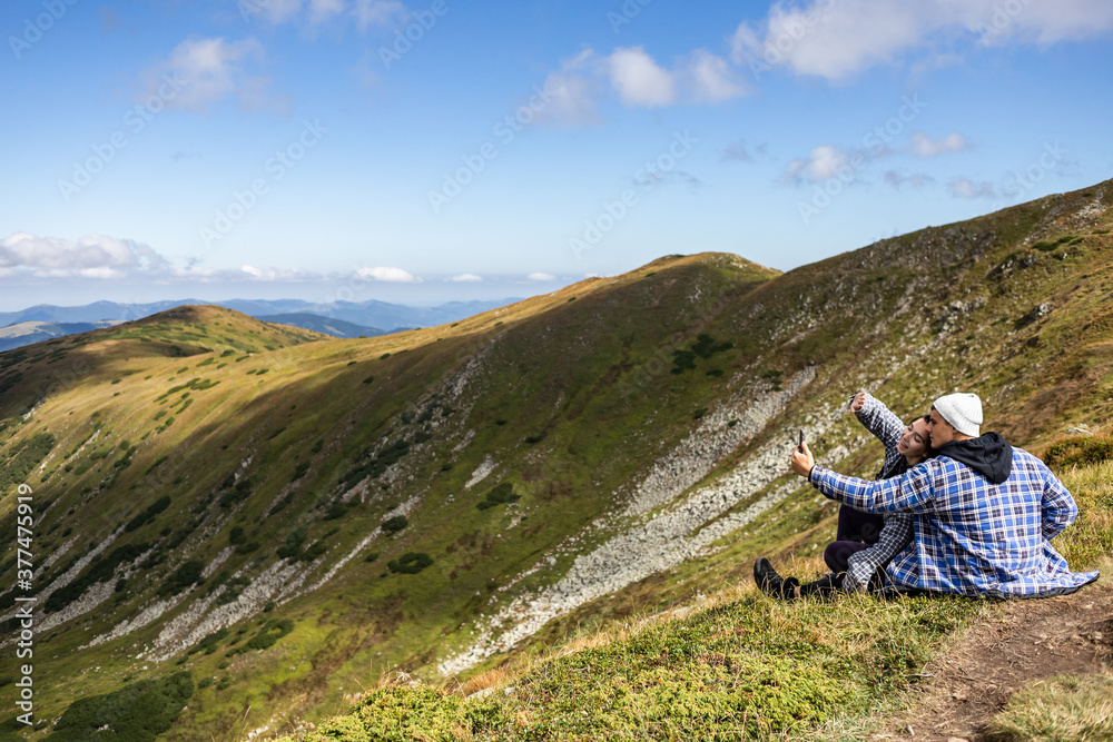 young couple travels and is photographed on a background of mountains
