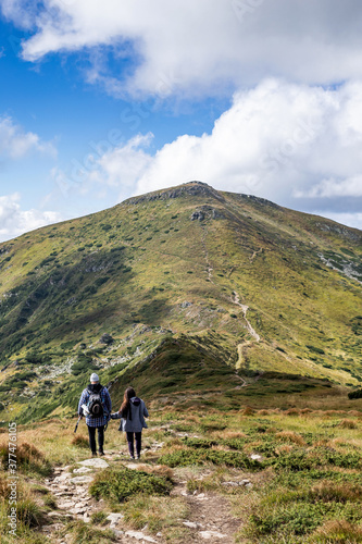 happy young couple traveling in the mountains, go up the trail