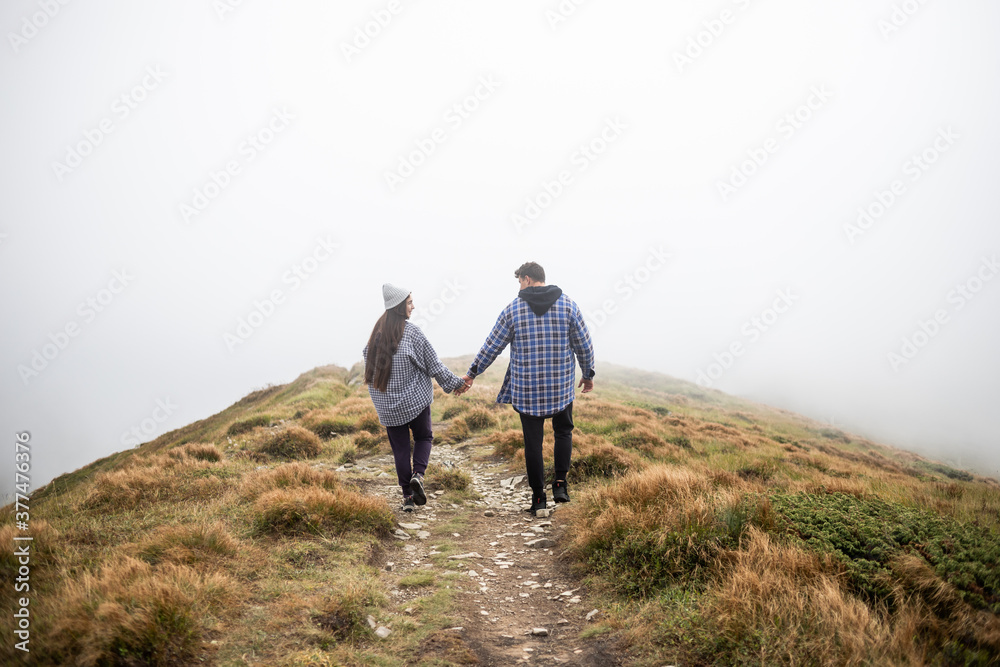 young couple traveling in the mountains, the road is in fog
