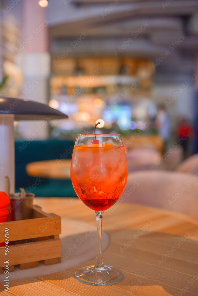 A glass with the red citrus cocktail. Alcohol summer beverage in a wine glass. Refreshing drink with ice. A glass with the red citrus cocktail. Alcohol summer beverage in a wine glass. Refreshing drink with ice.