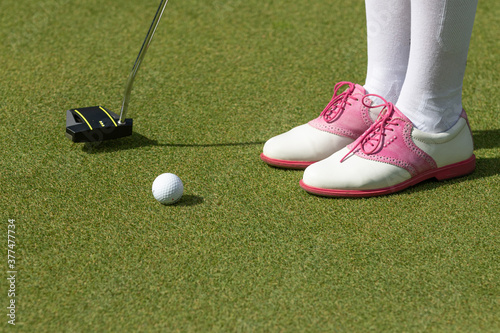 Golfer women preparing for a putt on the green during golf course. 
