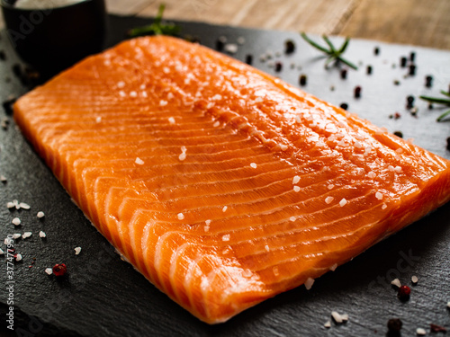 Fresh raw salmon fillet on black stone board 