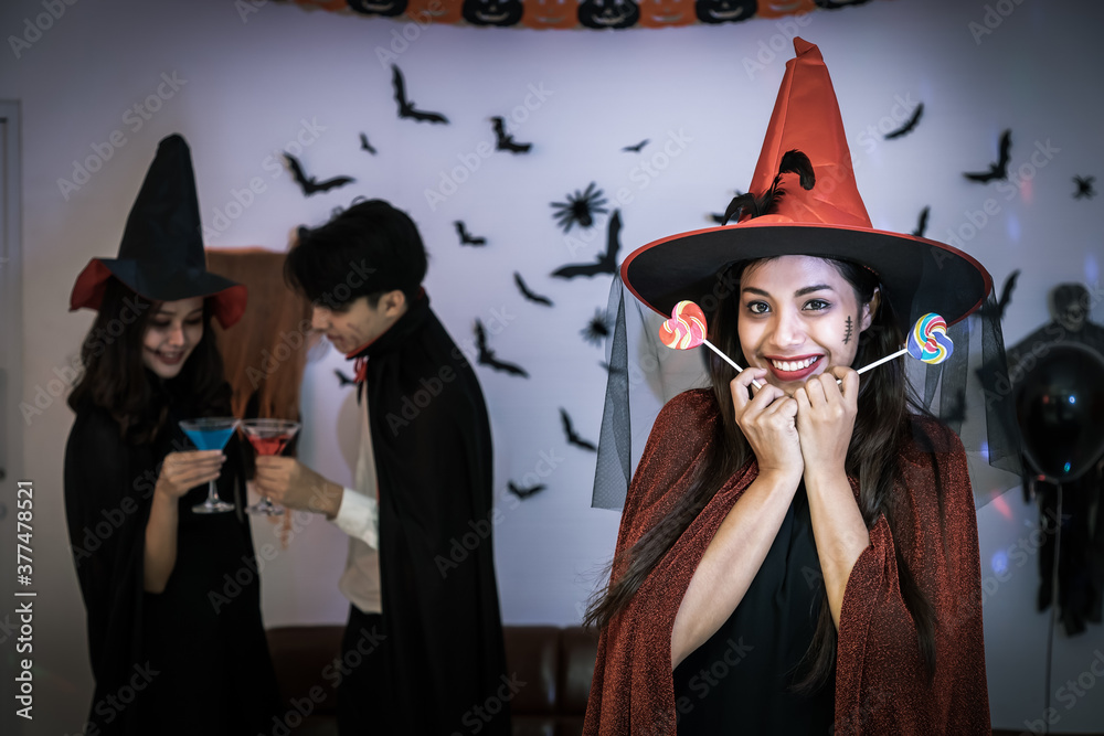 Portrait of young Asian woman smiling in Halloween costumer as witch in party, holding candy, looking at camera.