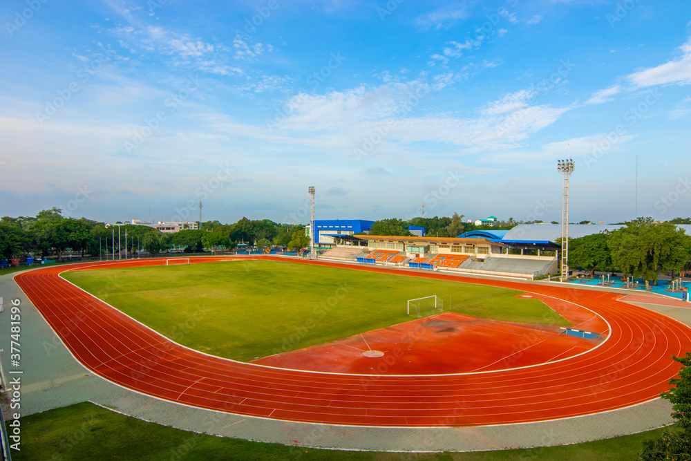 Red running track in sports fields and green grass