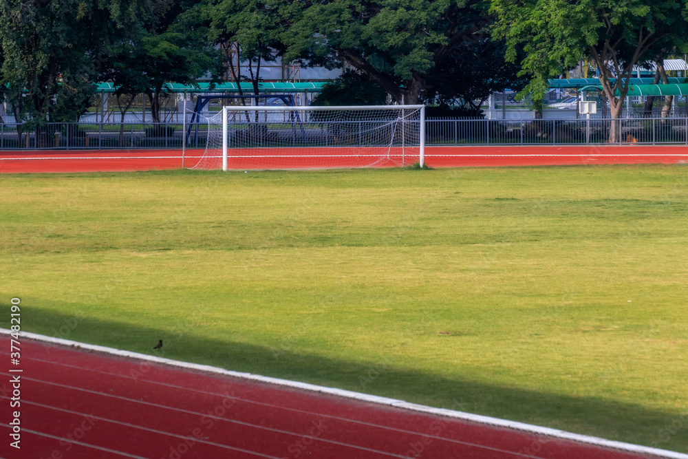 Fototapeta premium Red running track in sports fields and green grass