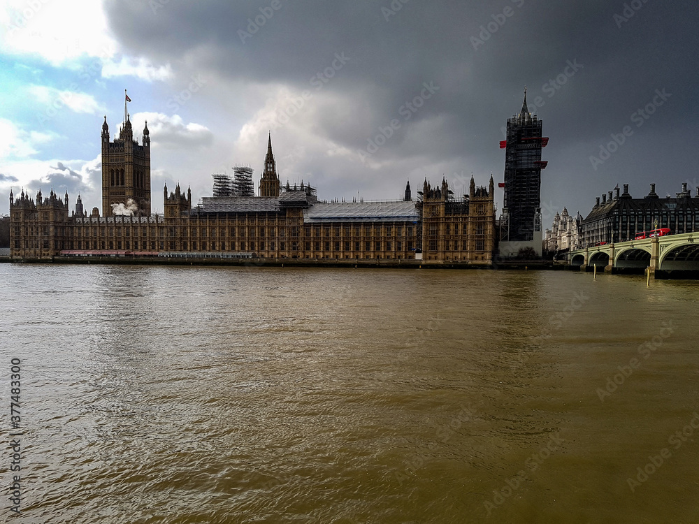 Naklejka premium Dark grey sky clouds storm coming or sun comes out winter day in London at westminster abbey bridge river thames big ben
