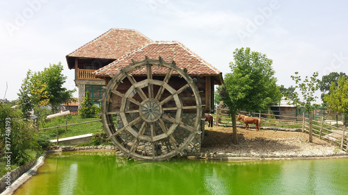 Old mill with a large wooden wheel in a landscaped tourist environment photo