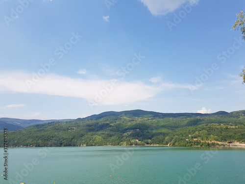 The green color of the water of a wide lake. The hilly coast is overgrown with forest