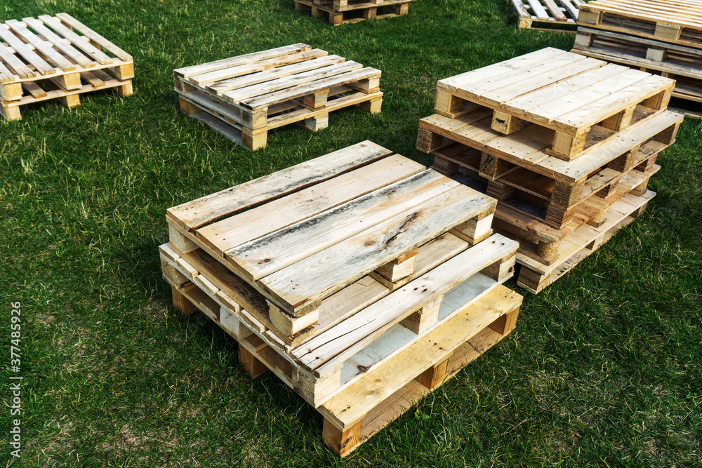 Wooden pallets lie on the lawn. Boxes from boards thrown away after use. Wooden pallets lie on the lawn. Boxes from boards thrown away after use.