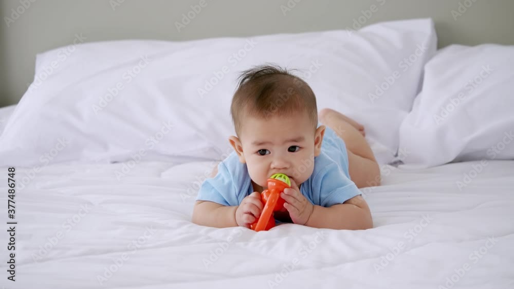 Adorable little baby playing a toy on bed. Adorable little baby playing a toy on bed.