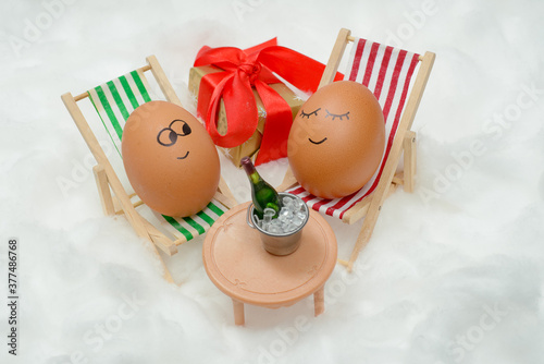 Funny lovely eggs in snow with gift box and bottle of wine