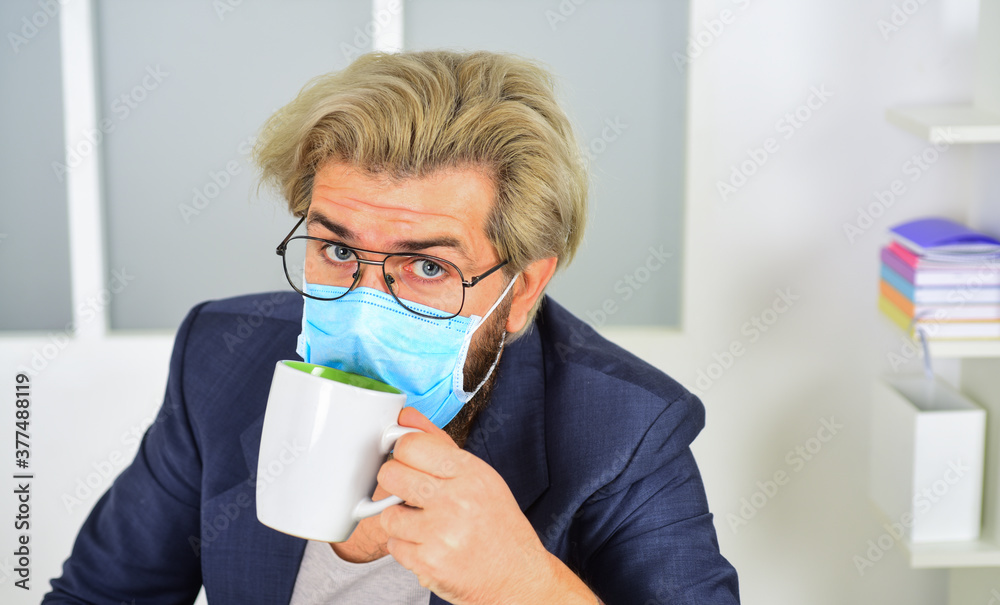 Virus transmitted by droplets and close contact. Wearing mask protect from coronavirus. Quarantine concept. Protect against coronavirus. Guy in mask drink tea or coffee at home. Man wear face mask Virus transmitted by droplets and close contact. Wearing mask protect from coronavirus. Quarantine concept. Protect against coronavirus. Guy in mask drink tea or coffee at home. Man wear face mask
