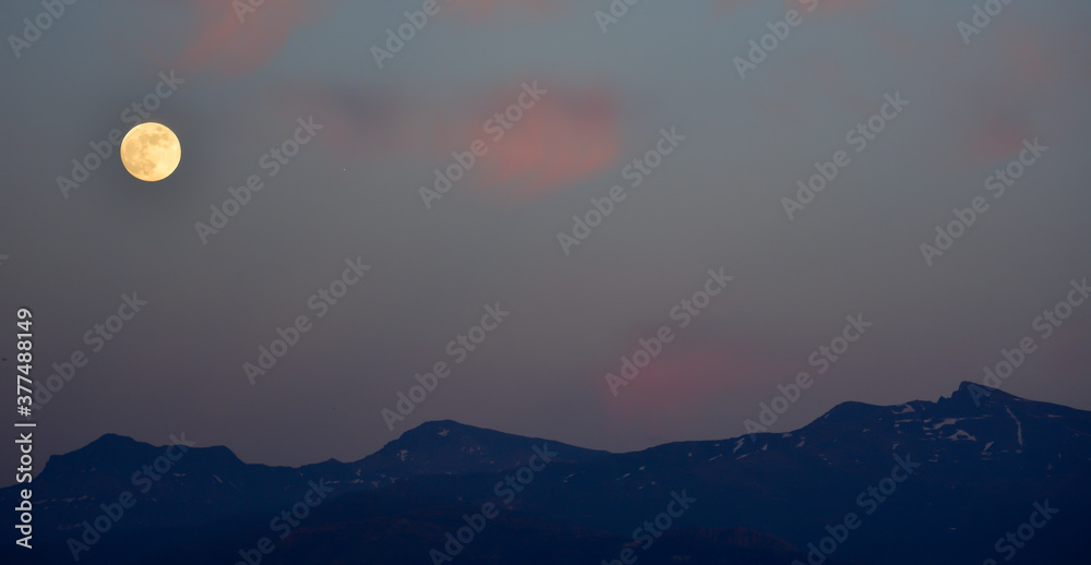 Full moon and pink clouds over the mountains Full moon and pink clouds over the mountains