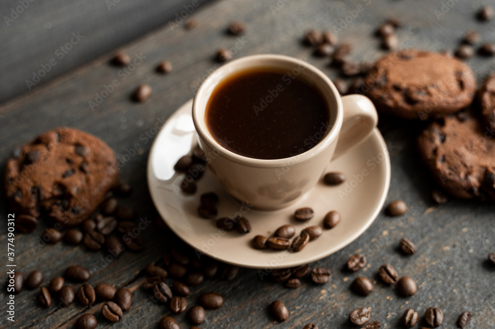 Coffee cup with cookies on wooden table background. Mug of black coffee with chocolate cookies. Fresh coffee beans. Coffee cup with cookies on wooden table background. Mug of black coffee with chocolate cookies. Fresh coffee beans.