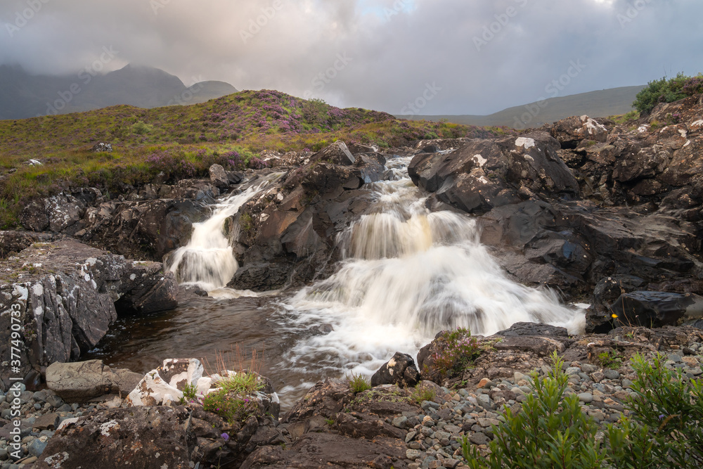 Beautiful Sligachan waterfalls on the Isle of Skye in the Highlands of Scotland, the Cuillin mountains rising behind lit by sunset Beautiful Sligachan waterfalls on the Isle of Skye in the Highlands of Scotland, the Cuillin mountains rising behind lit by sunset