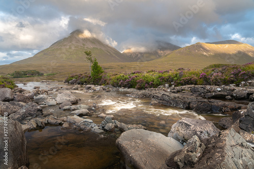 Beautiful Sligachan waterfalls on the Isle of Skye in the Highlands of Scotland  the Cuillin mountains rising behind lit by sunset