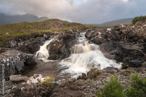 Beautiful Sligachan waterfalls on the Isle of Skye in the Highlands of Scotland  the Cuillin mountains rising behind lit by sunset