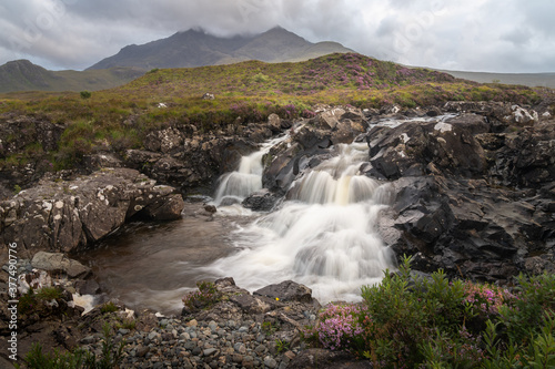 Beautiful Sligachan waterfalls on the Isle of Skye in the Highlands of Scotland, the Cuillin mountains rising behind lit by sunset