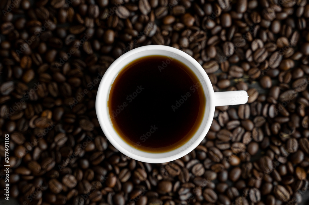 White cup of coffee with roasted coffee beans background. Mug of black coffee. White cup of coffee with roasted coffee beans background. Mug of black coffee.