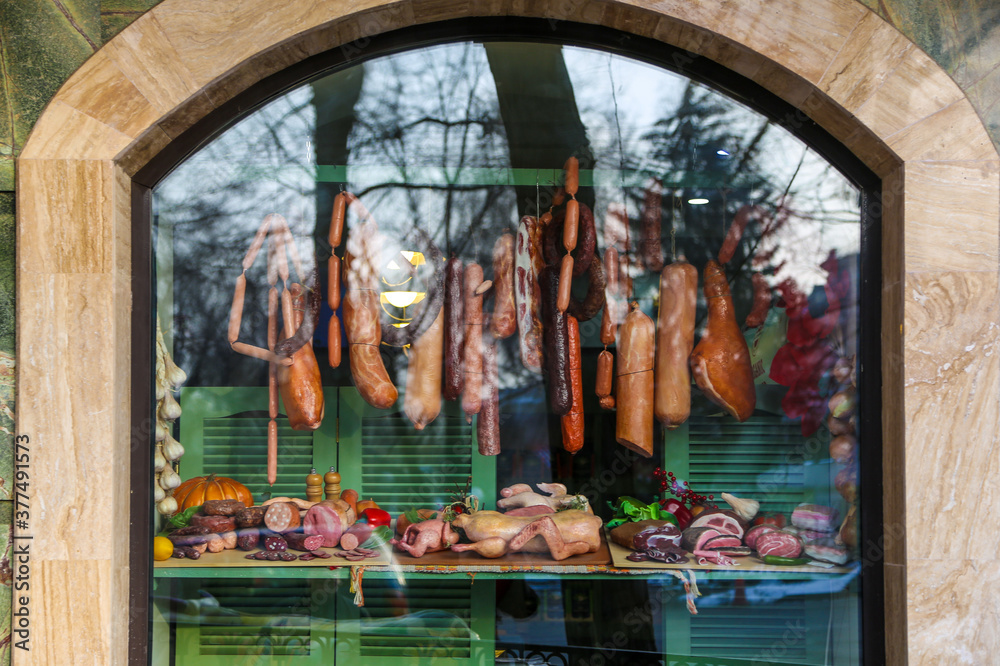 Colorful butcher shop display showing various meat behind a window with