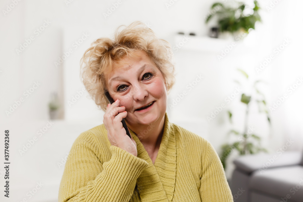 Concept of easy, fast usage of modern technology among all ages. Portrait of confident mature woman with wrinkles she is using her modern smartphone for sending a message isolated on gray background Concept of easy, fast usage of modern technology among all ages. Portrait of confident mature woman with wrinkles she is using her modern smartphone for sending a message isolated on gray background