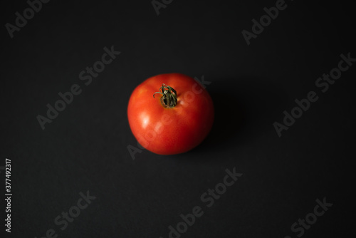 Red ripe fresh tomato on a black background.