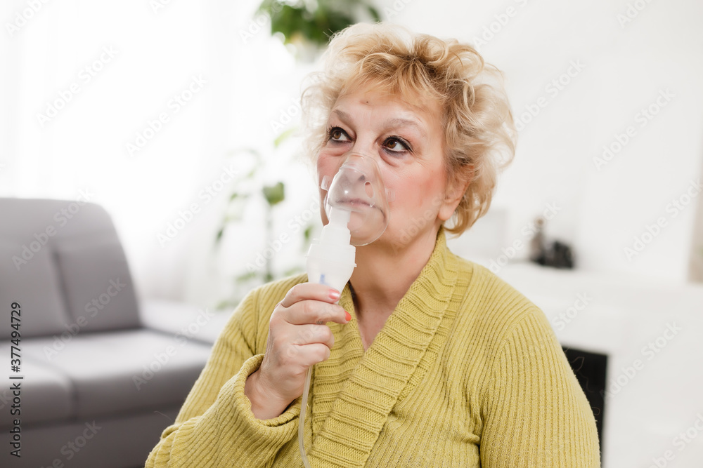 Elderly woman using asthma machine on light background Elderly woman using asthma machine on light background