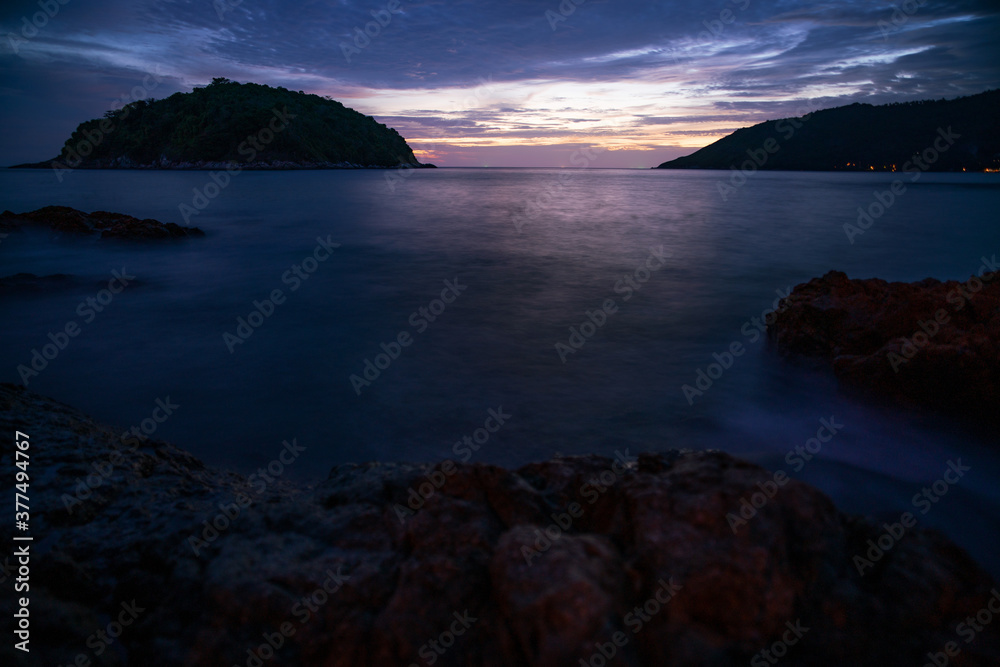 Long exposure image of Dramatic sky seascape with rocks in the foreground sunset or sunrise scenery background.
