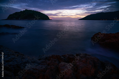 Long exposure image of Dramatic sky seascape with rocks in the foreground sunset or sunrise scenery background.