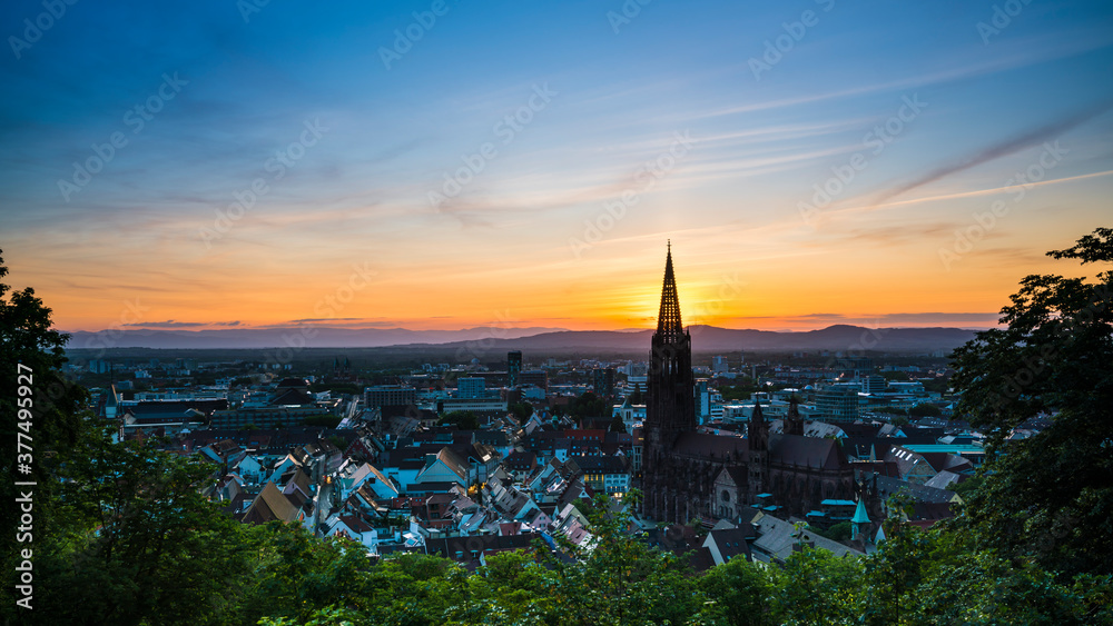Germany, Freiburg im Breisgau, Beautiful orange sunset behind steeple of the famous minster cathedral, aerial view from above