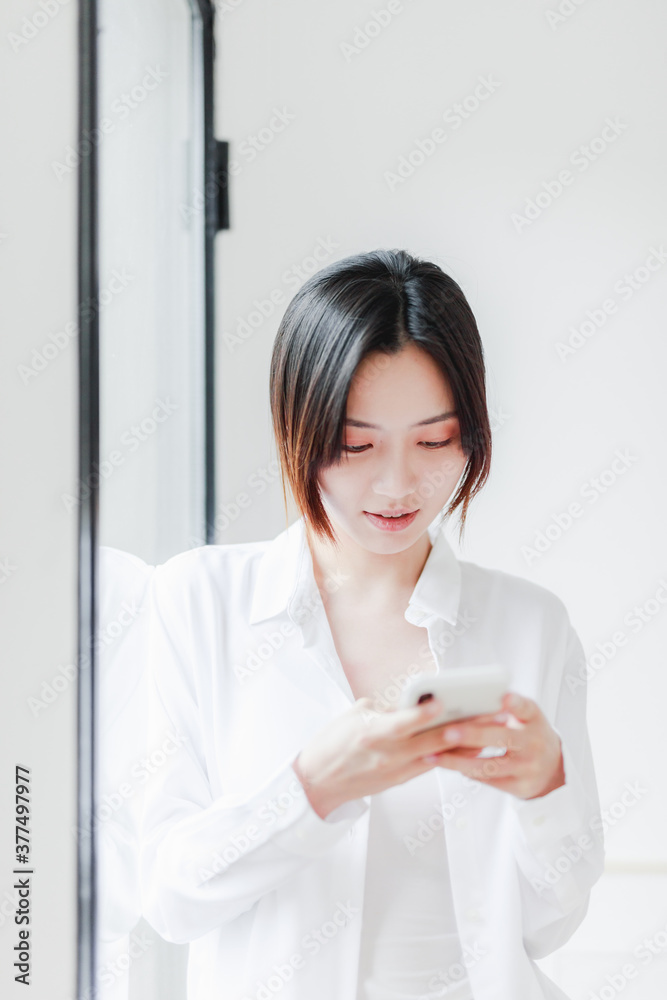 Asian women use mobile phones by French windows Asian women use mobile phones by French windows