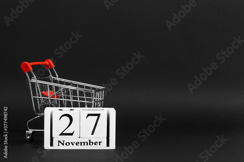 The calendar is November 27, and shopping cart on a black background, the concept layout to Black Friday. Copy space.