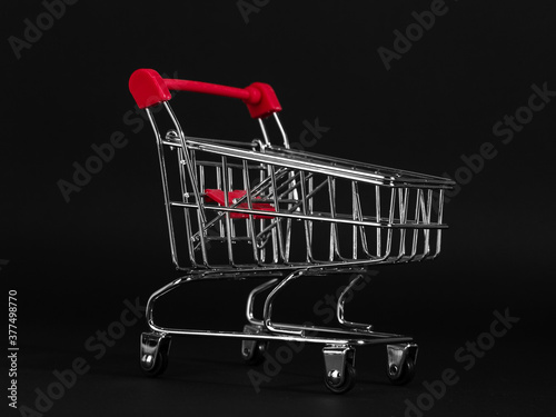 Shopping cart on a black background, a blank for the design, concept. Copy space.