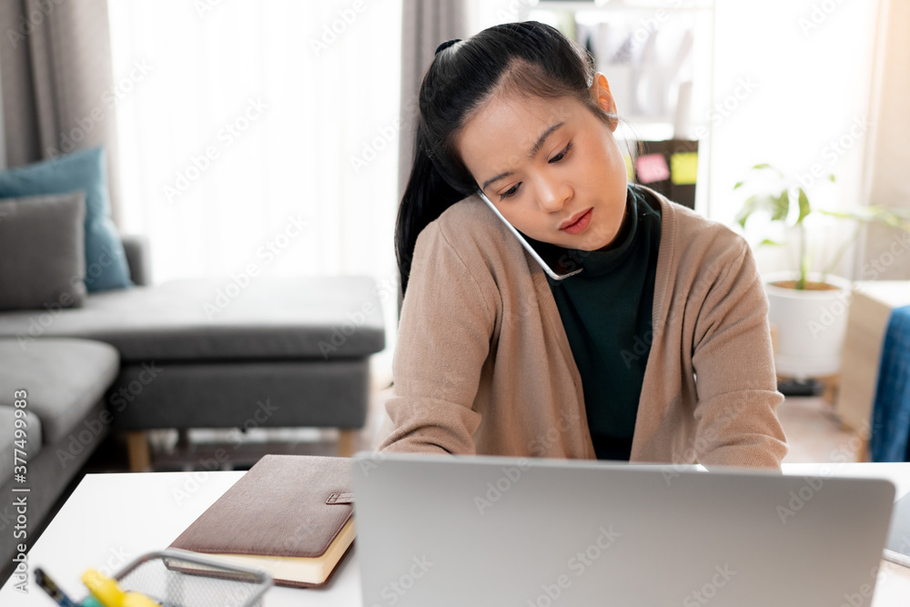 Woman talking with someone on mobile phone while working with laptop Woman talking with someone on mobile phone while working with laptop