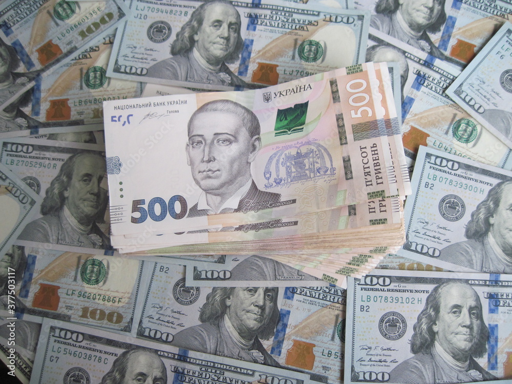 Financial background with a lot of paper banknotes of USA 100 dollars and Ukraine 500 hryvnia is great for editorial publication about money exchange. 